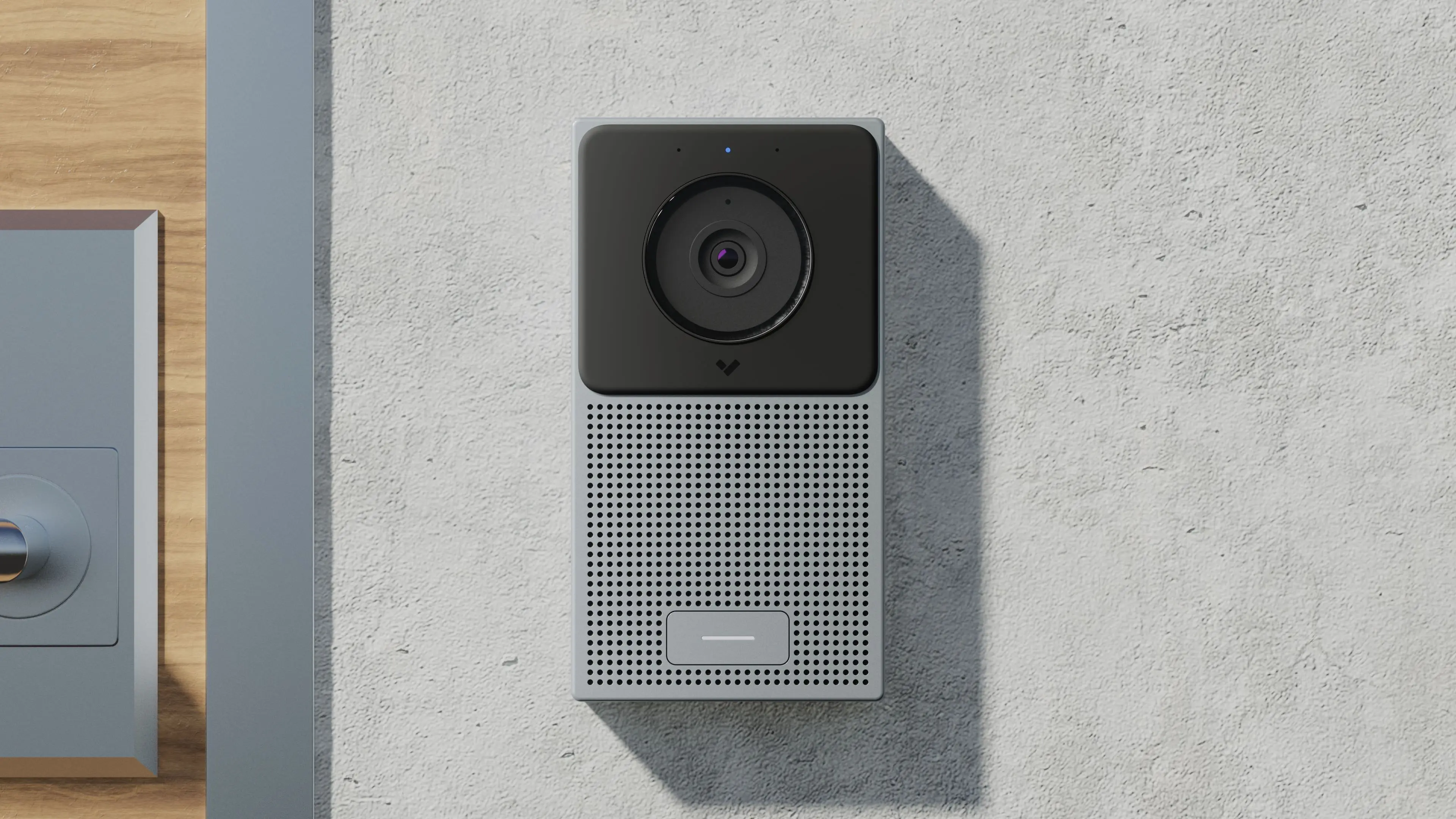 Modern silver and black smart video doorbell mounted on a textured light gray wall.