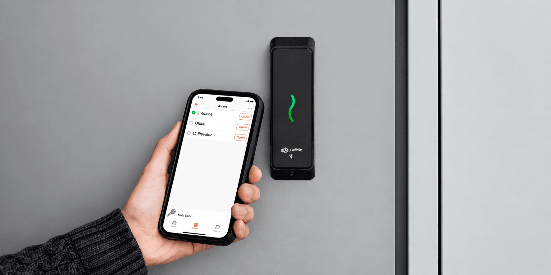 Hand holding a smartphone with an access app near a Gallagher wall-mounted security reader.