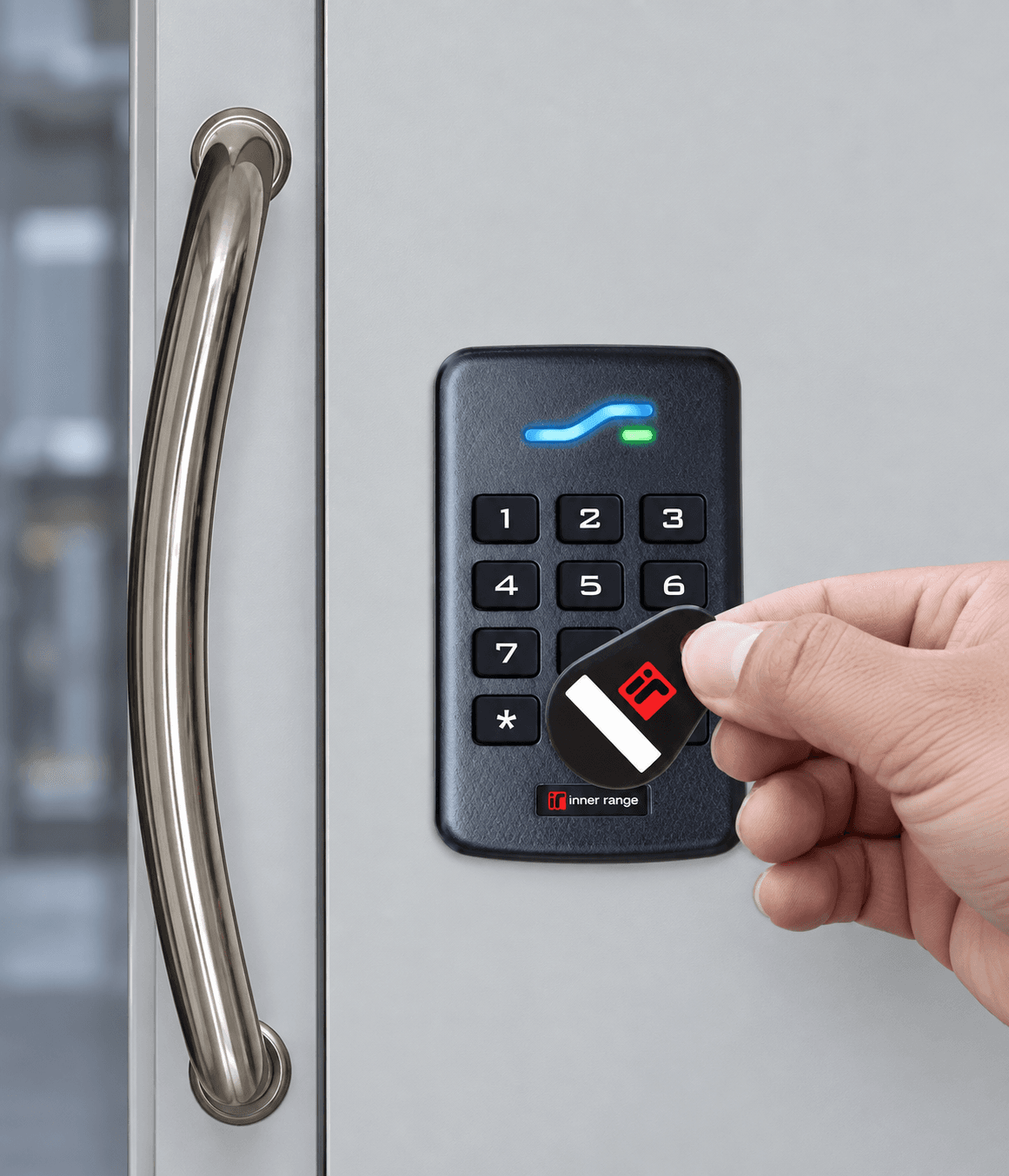 Hand scanning a key fob on an Inner Range electronic keypad reader for secure access.
