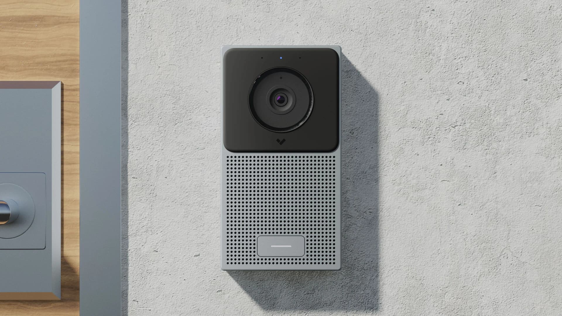 Modern silver and black video doorbell with a large camera lens mounted on a textured wall.
